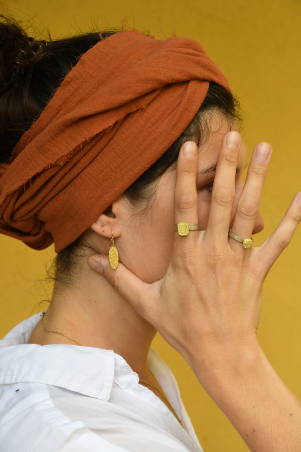 Frau mit orangenem Tuch im Haar trägt ausdrucksstarke Ringe aus Gold und Silber die gleichzeitig sehr fein gearbeitet sind