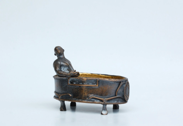 Ein Mann sitz in einer Badewanne aus Bronze. Die Wanne ist innen vergoldet.